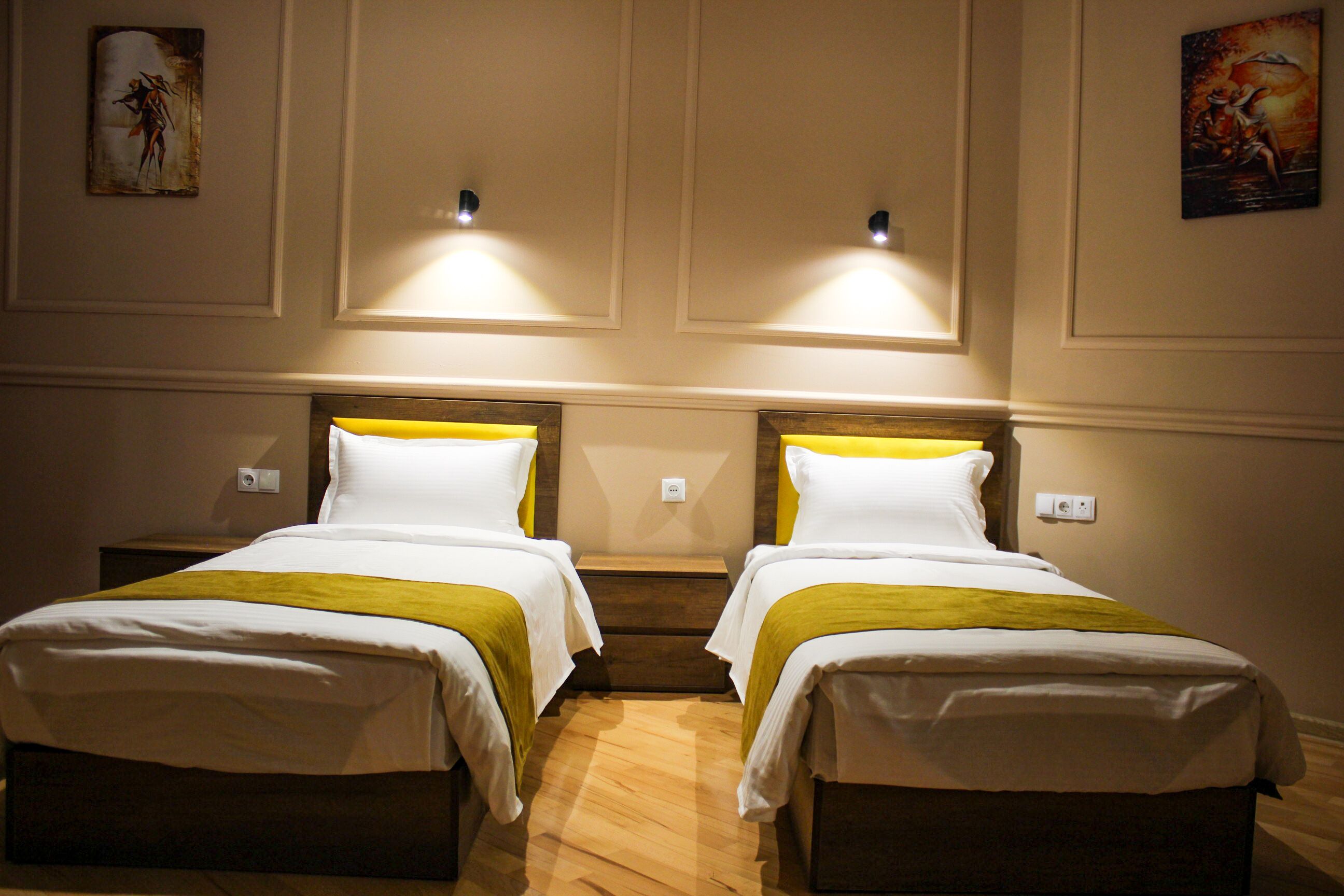 A hotel room with two single beds, each with a wooden headboard and white bedding.
