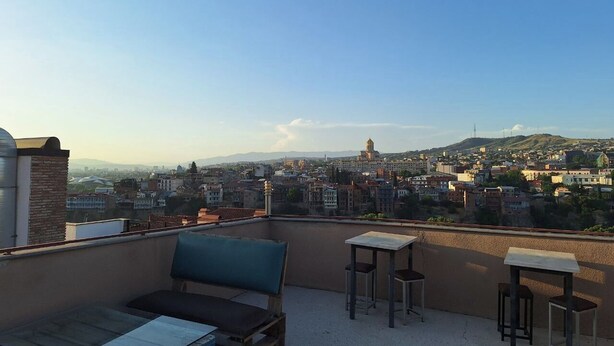 A rooftop terrace with a view of a cityscape, including a prominent tower. - Hugo Boutique Hotel (Tbilisi)