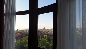 A view through a window with a cityscape, including buildings and trees, visible outside. - Hugo Boutique Hotel (Tbilisi)