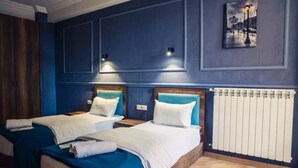 A hotel room with two beds, each with a headboard and white bedding. There is a radiator on the wall and a framed picture above the beds. - Hugo Boutique Hotel (Tbilisi)