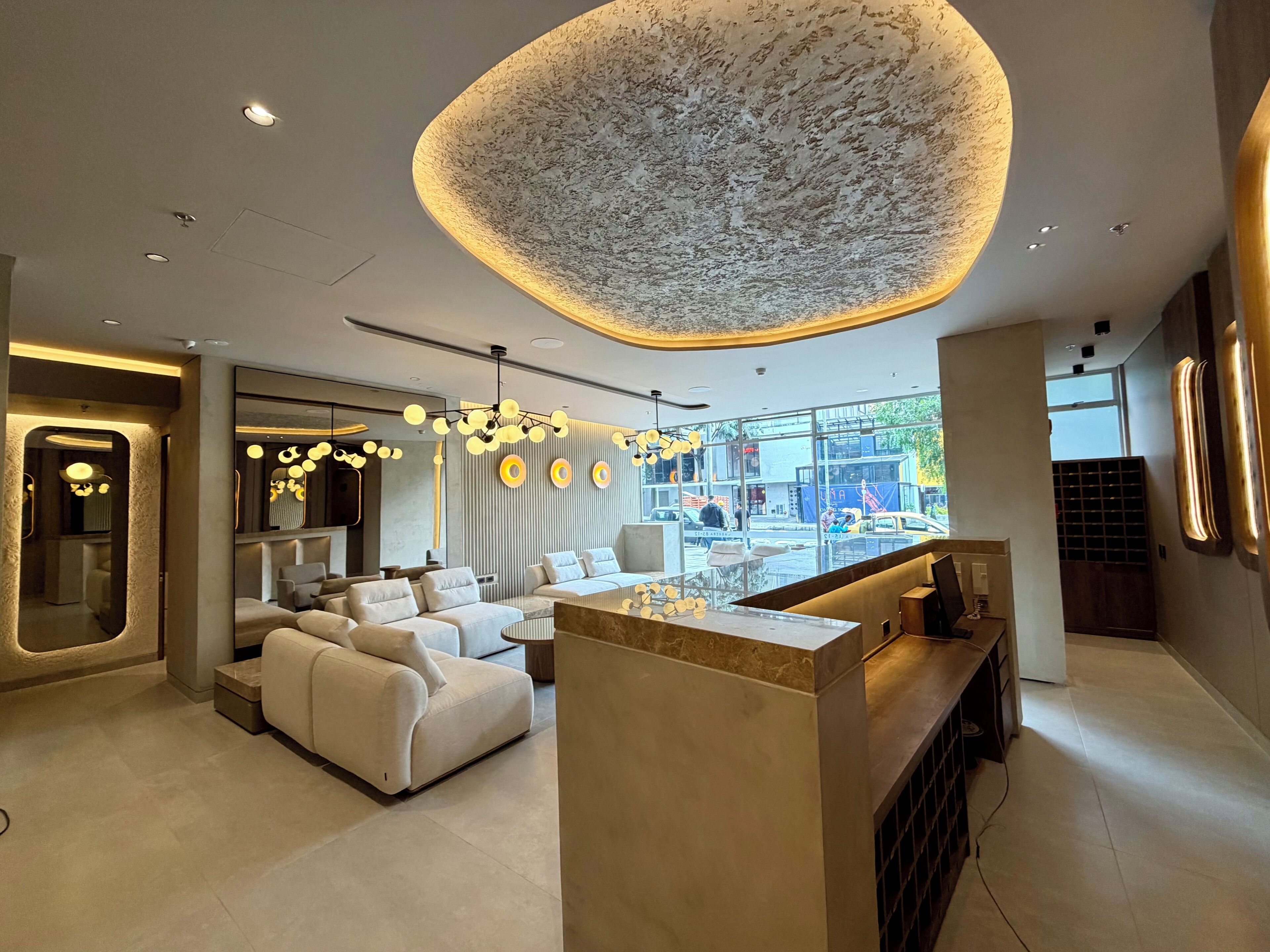 A modern interior with a central seating area, a unique ceiling light, and a view through large windows.