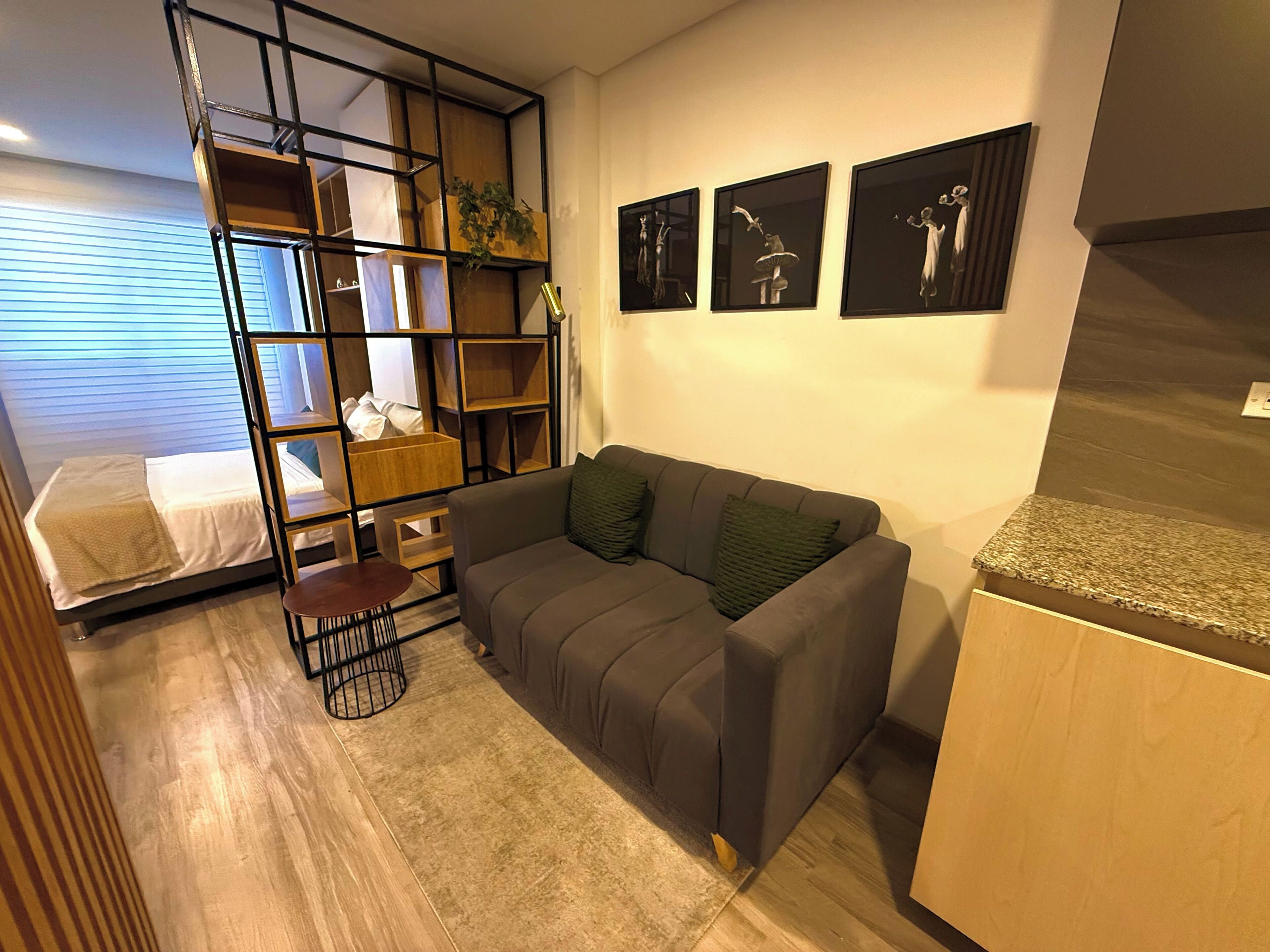 A compact living space with a sofa, a small table, a bed, and a built-in shelving unit.