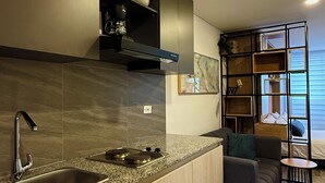 A modern kitchen with a built-in stove, sink, and overhead cabinets. There is a seating area with a sofa and a small table. - Modern Loft in 85st near Andino (Bogotá)