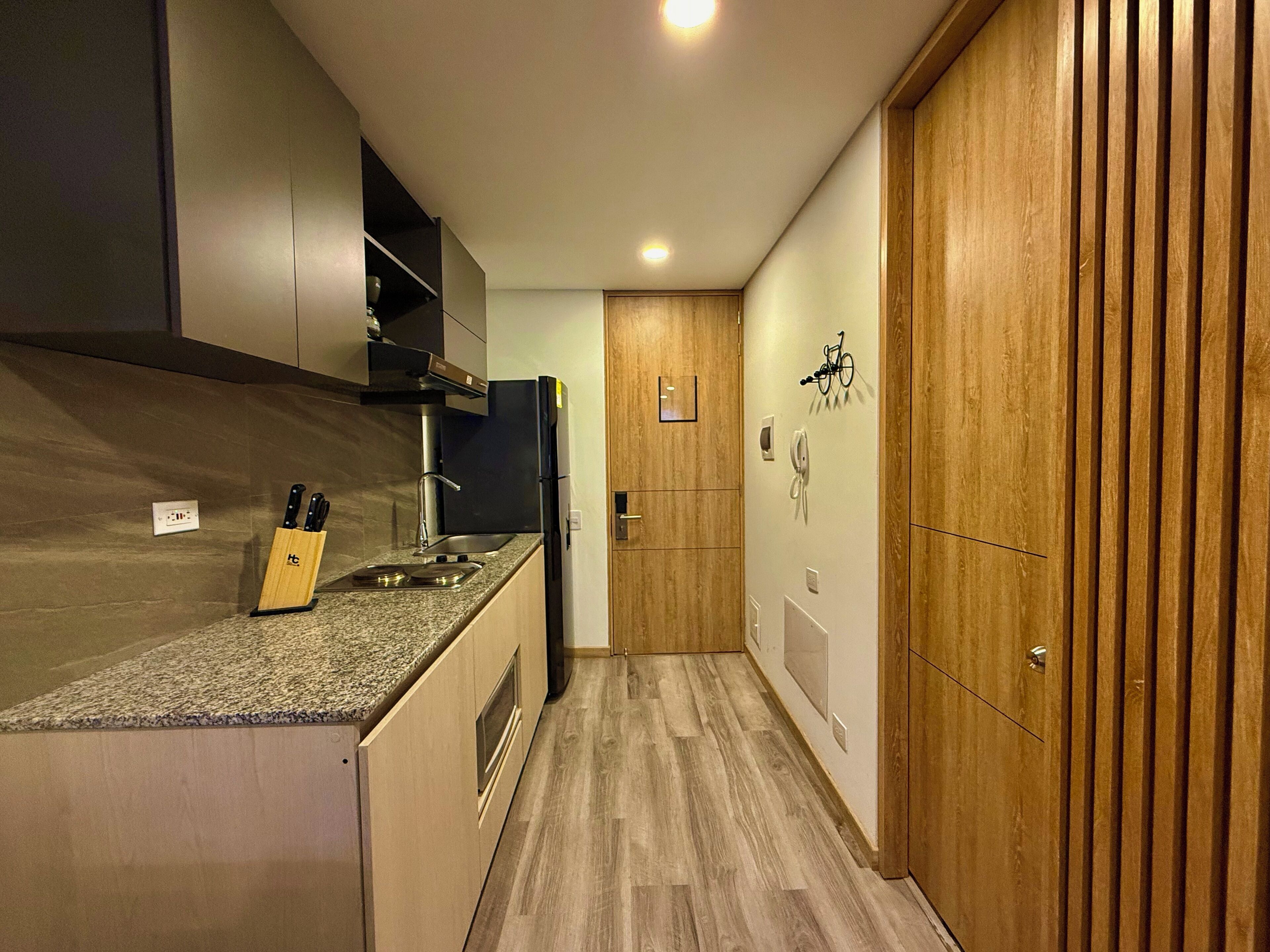 A modern kitchen with a granite countertop, stainless steel appliances, and wooden cabinetry.