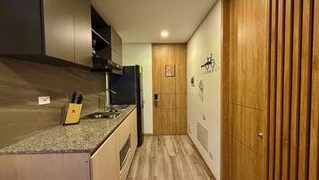 Cozinha moderna com bancada de granito, eletrodomésticos de aço inoxidável e armários de madeira.