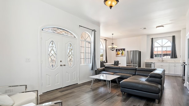 A modern living room with a sectional sofa, a coffee table, and a dining area with a white table and chairs.