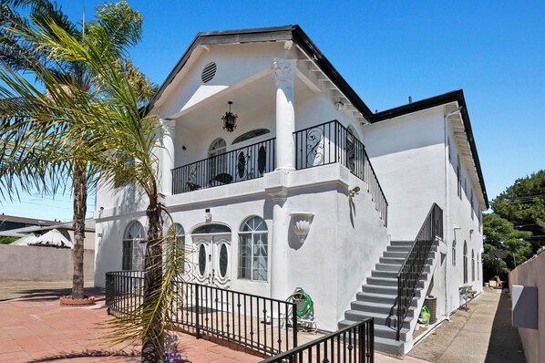 A two-story building with a balcony, arched windows, and a staircase.