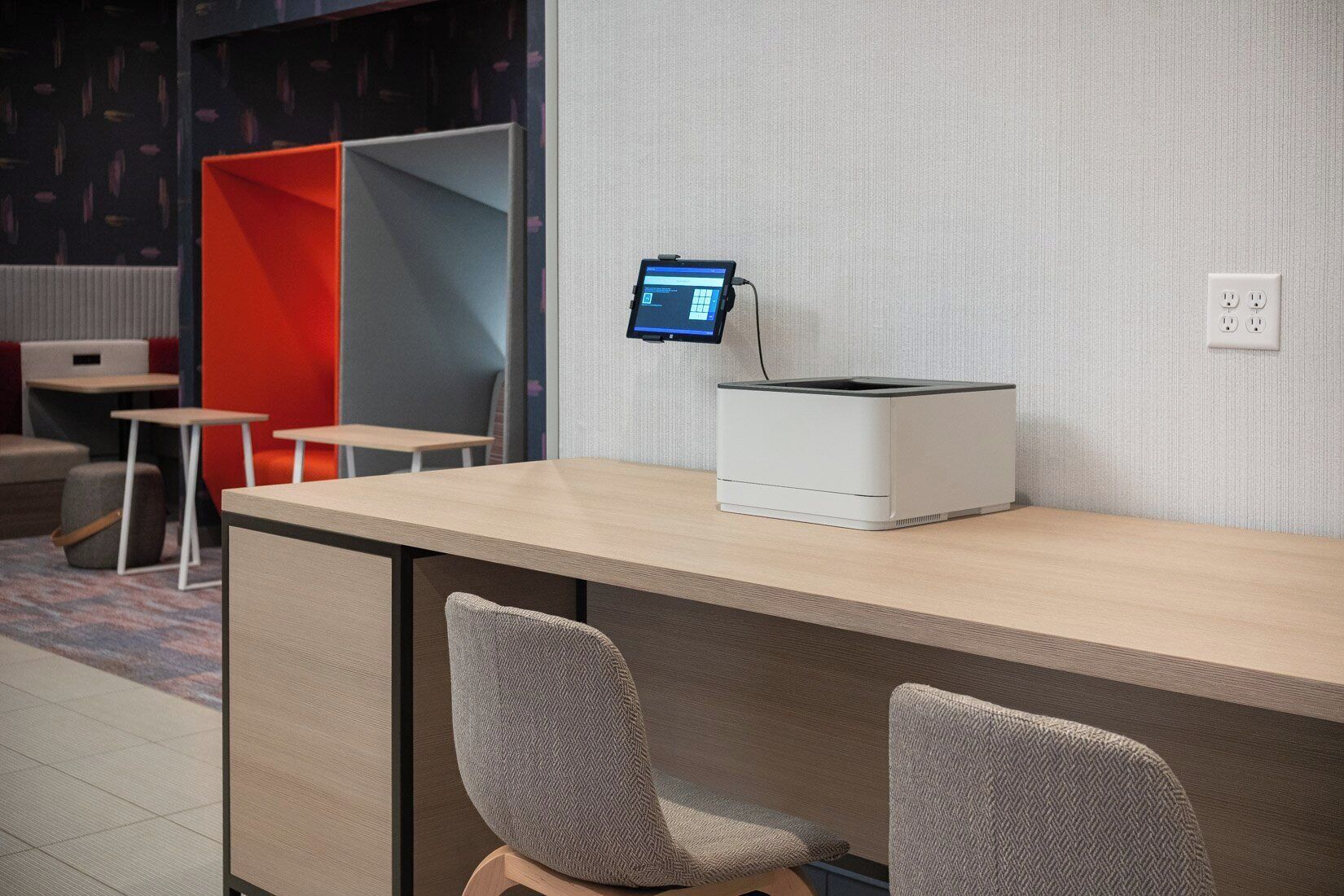 A modern office space with a desk, two chairs, a computer monitor, and a printer.