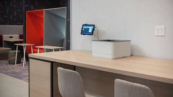 A modern office space with a desk, two chairs, a computer monitor, and a printer.