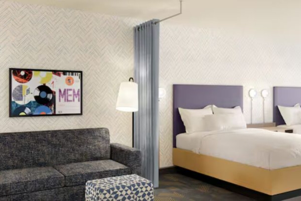 Una habitación de hotel con cama, sofá y una mesita.