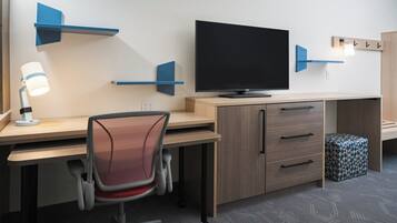 A modern office desk with a flat-screen TV, a desk lamp, and a chair.