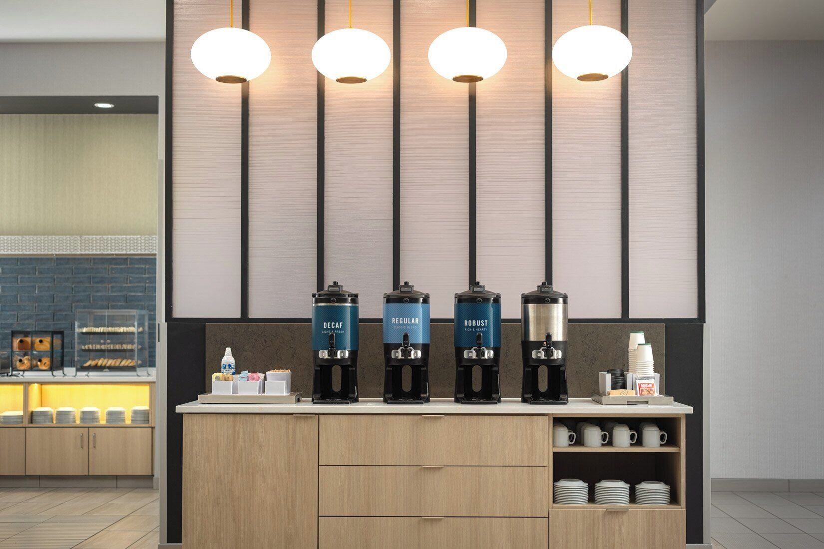 A coffee station with four dispensers labeled 'DECAF,' 'REGULAR,' 'ROBUST,' and 'LIGHT & FRESH.'