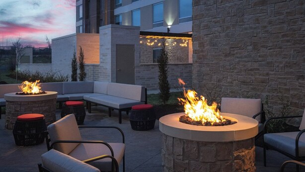 Un área de estar al aire libre con chimeneas de piedra y mobiliario moderno.