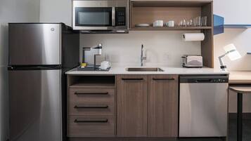 A compact kitchen with a refrigerator, microwave, coffee maker, sink, and dishwasher.