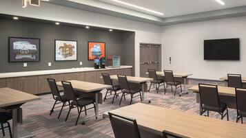 A conference room with tables, chairs, a flat-screen TV, and artwork on the wall.