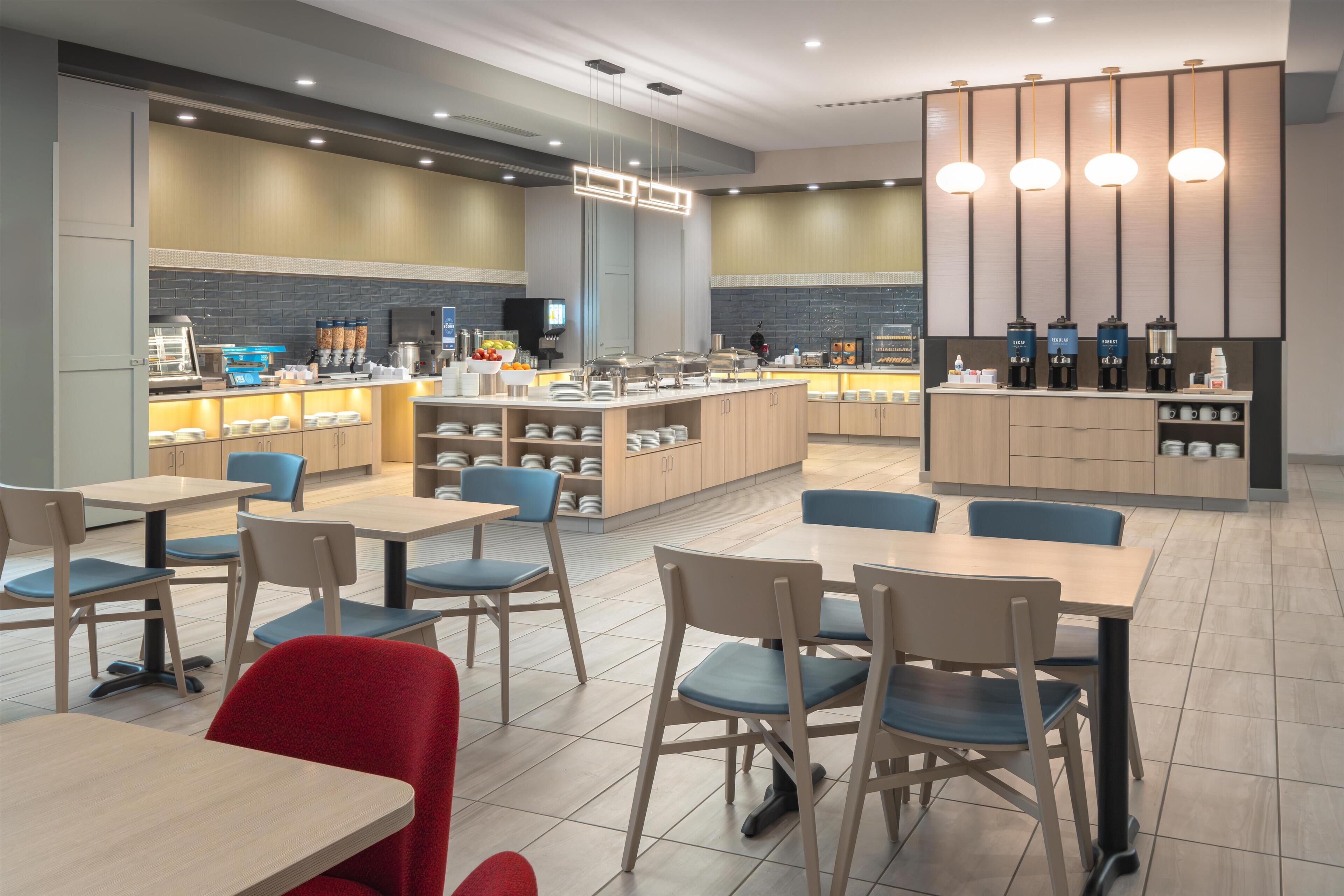 Un café moderne avec un comptoir central, un espace salon et un coin dédié à la préparation du café.