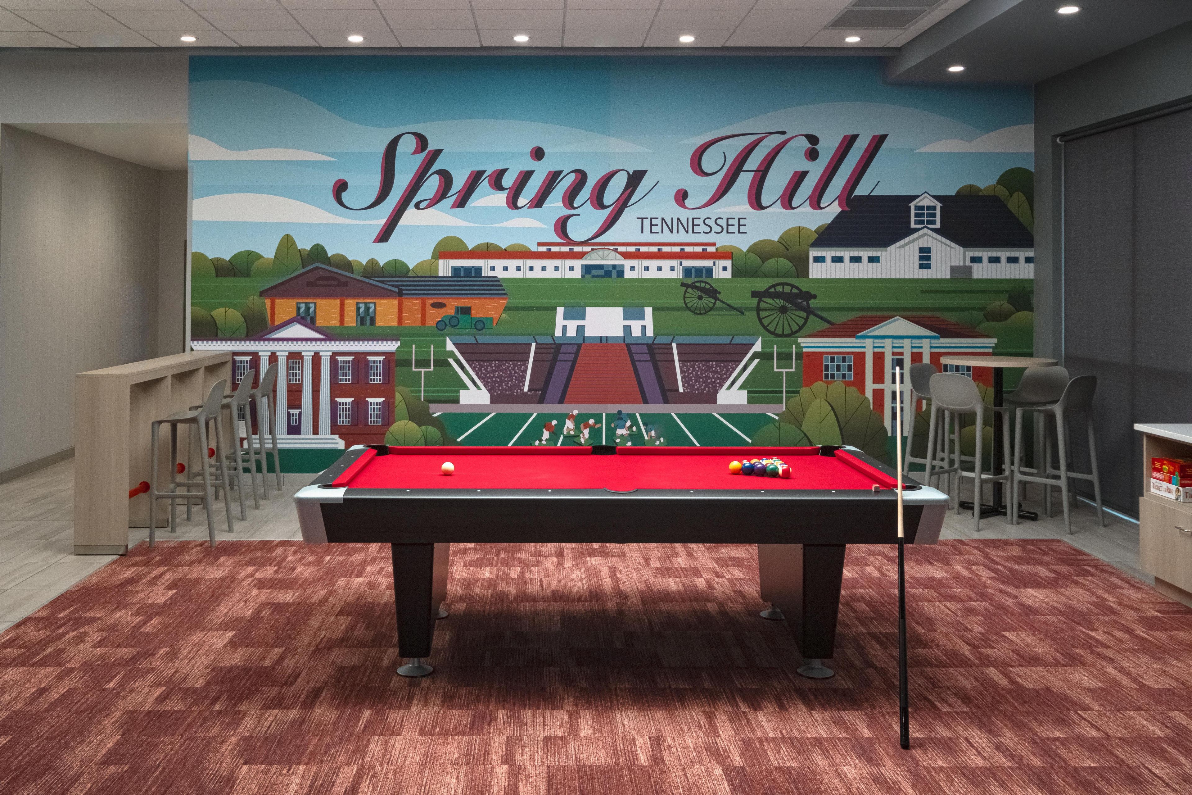 A pool table in a room with a mural of Spring Hill, Tennessee.