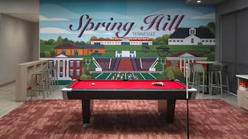 A pool table in a room with a mural of Spring Hill, Tennessee.