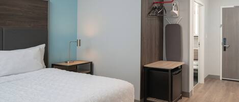 A modern bedroom with a large bed, a bedside table, a small desk, and a wardrobe.