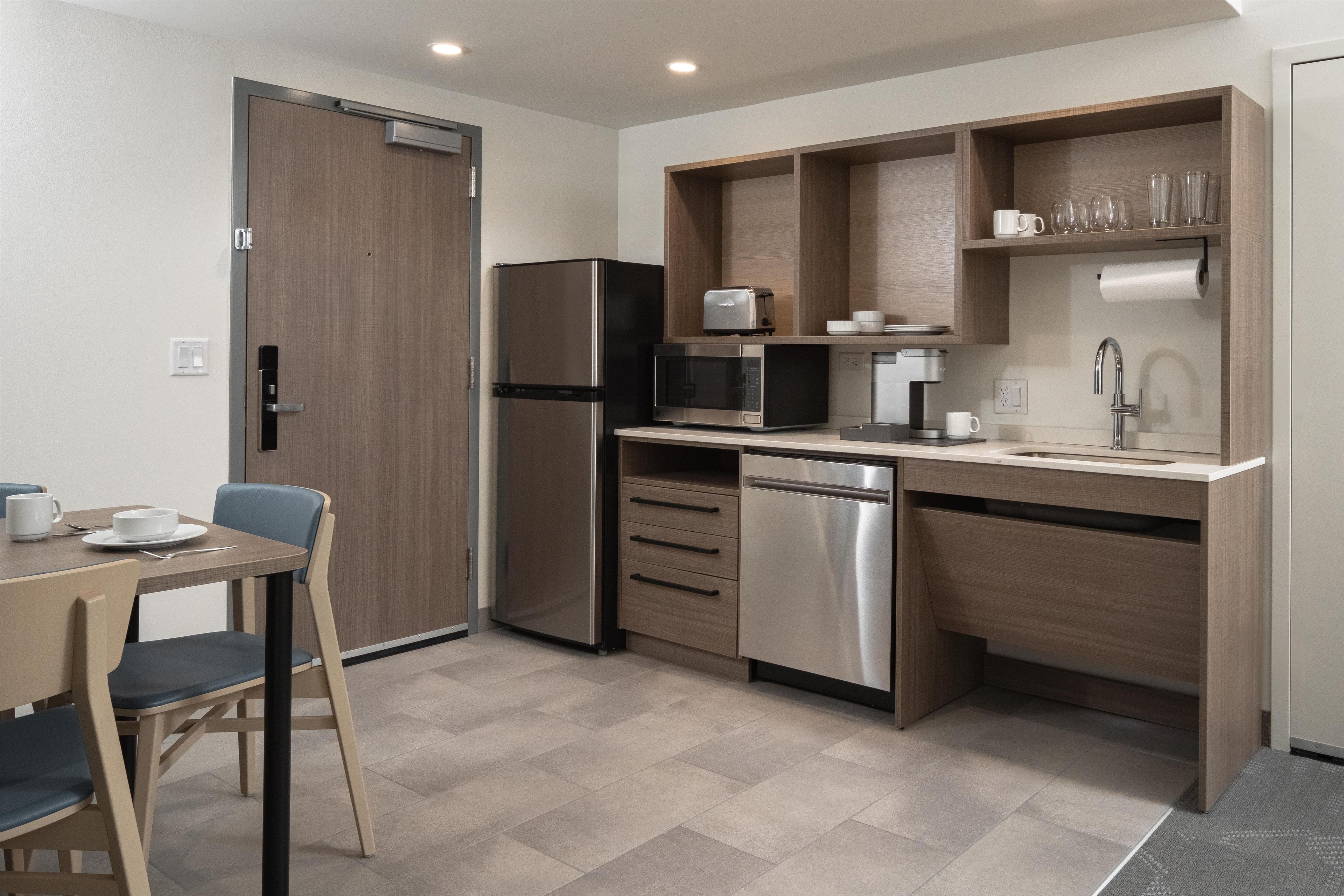 A compact kitchenette with a refrigerator, microwave, toaster, and coffee maker.