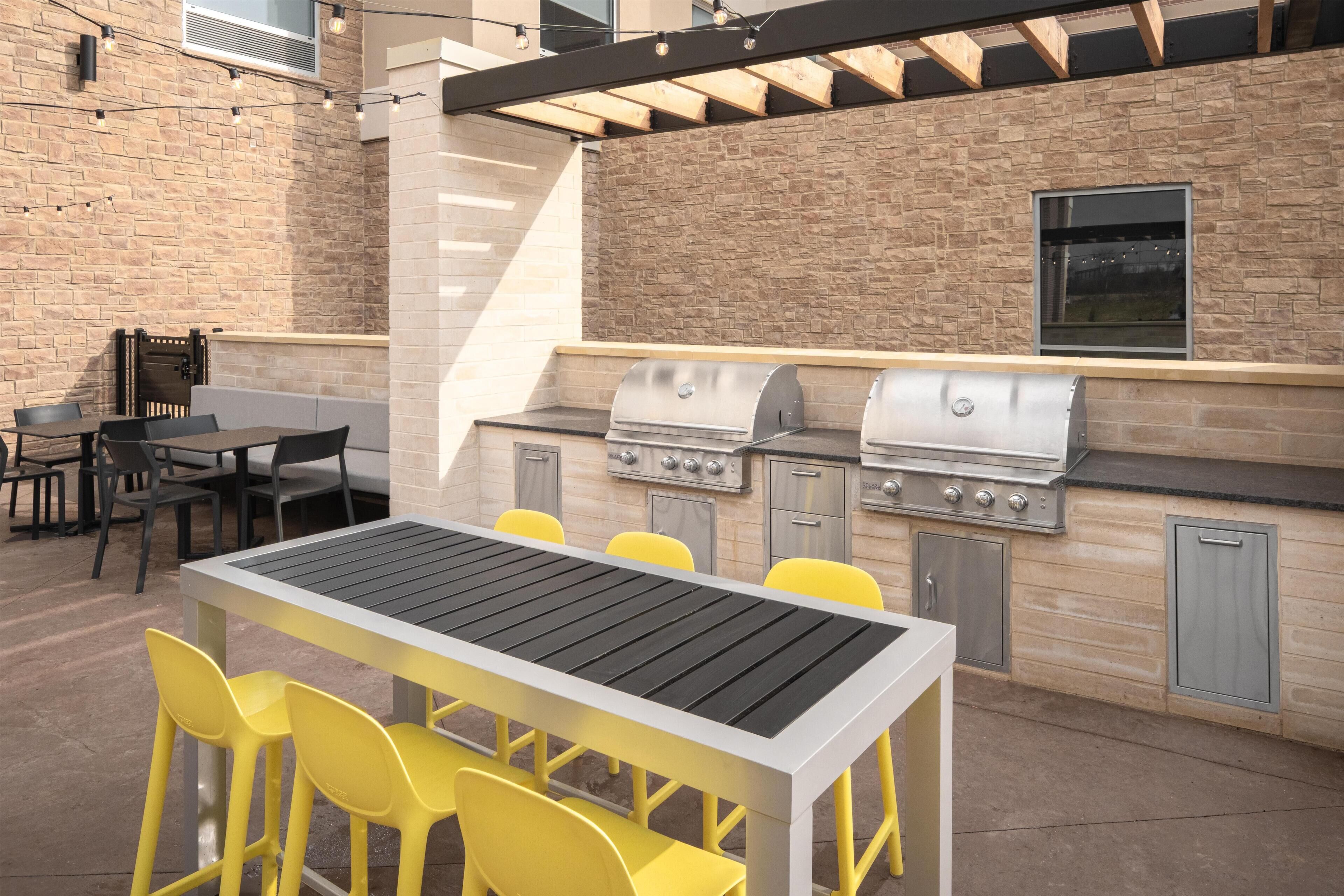 Un patio exterior con una parrilla, asientos y una pared de ladrillo.