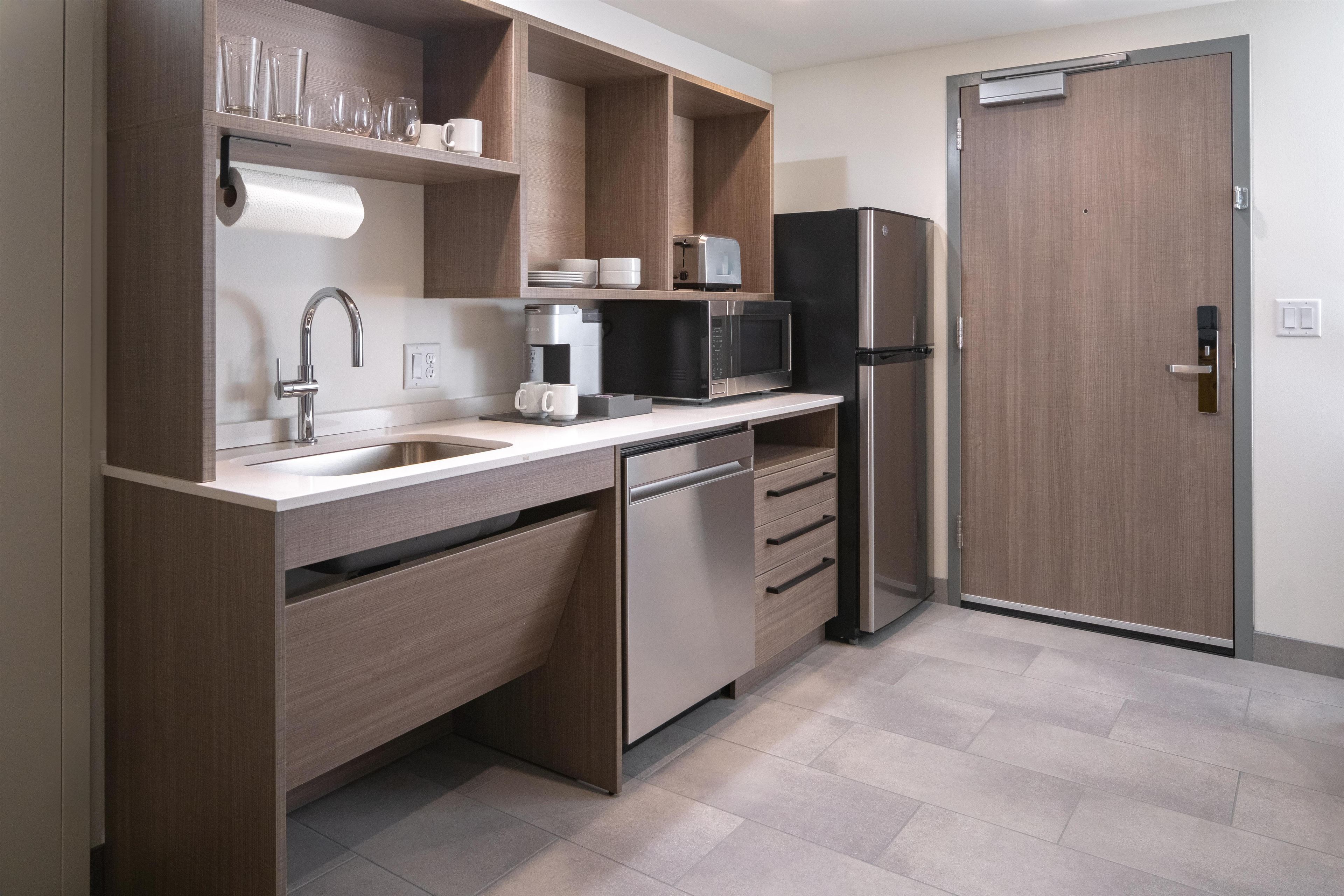 A modern kitchen with a built-in dishwasher, a microwave, a refrigerator, and a sink.