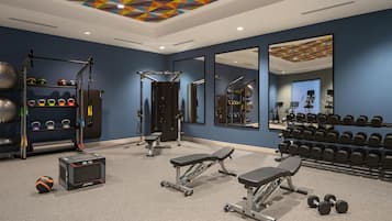 A gym with various exercise equipment, including dumbbells, a bench, and weight machines.