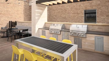 Un patio exterior con una parrilla, zona de estar y ventanal con vistas a la calle.