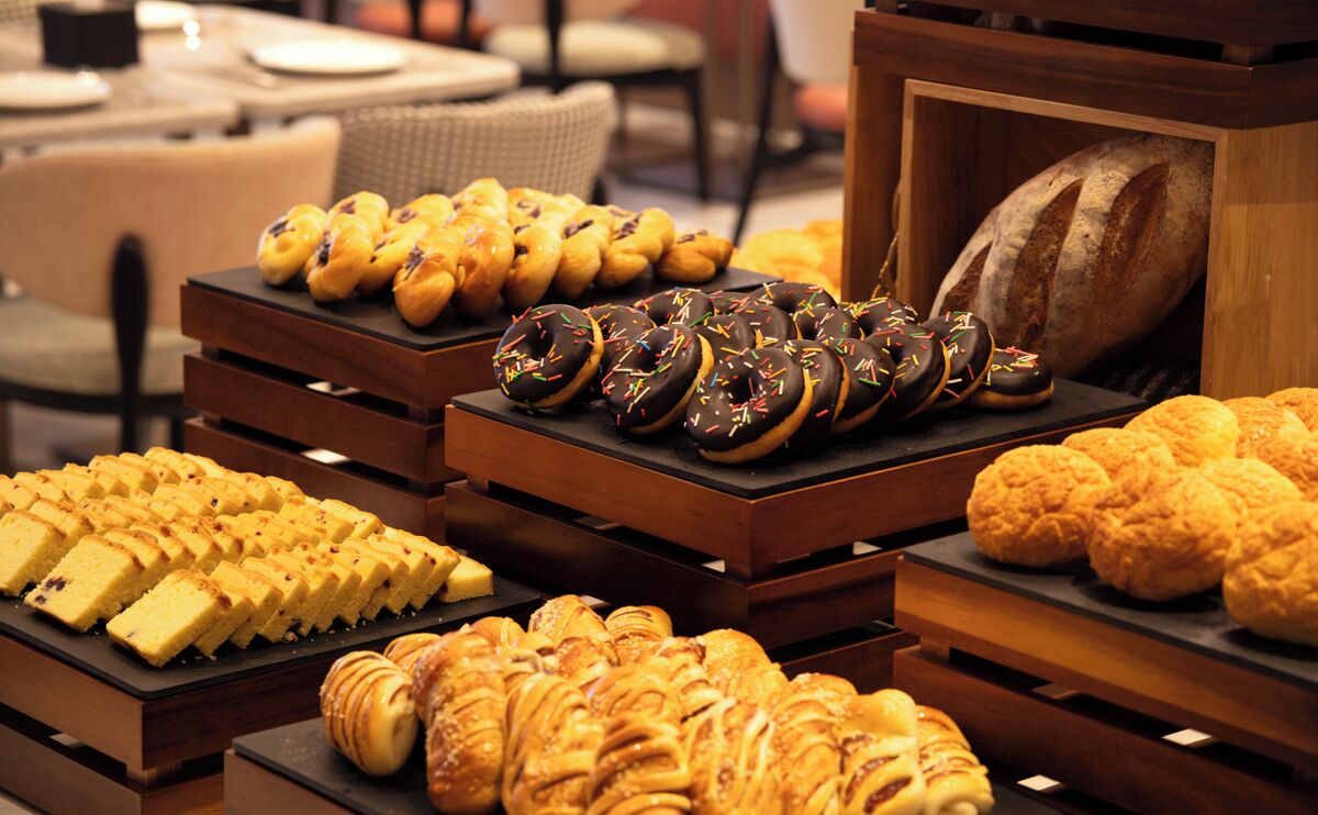 Una vitrina de pastelería con diversos pasteles y una hogaza de pan.
