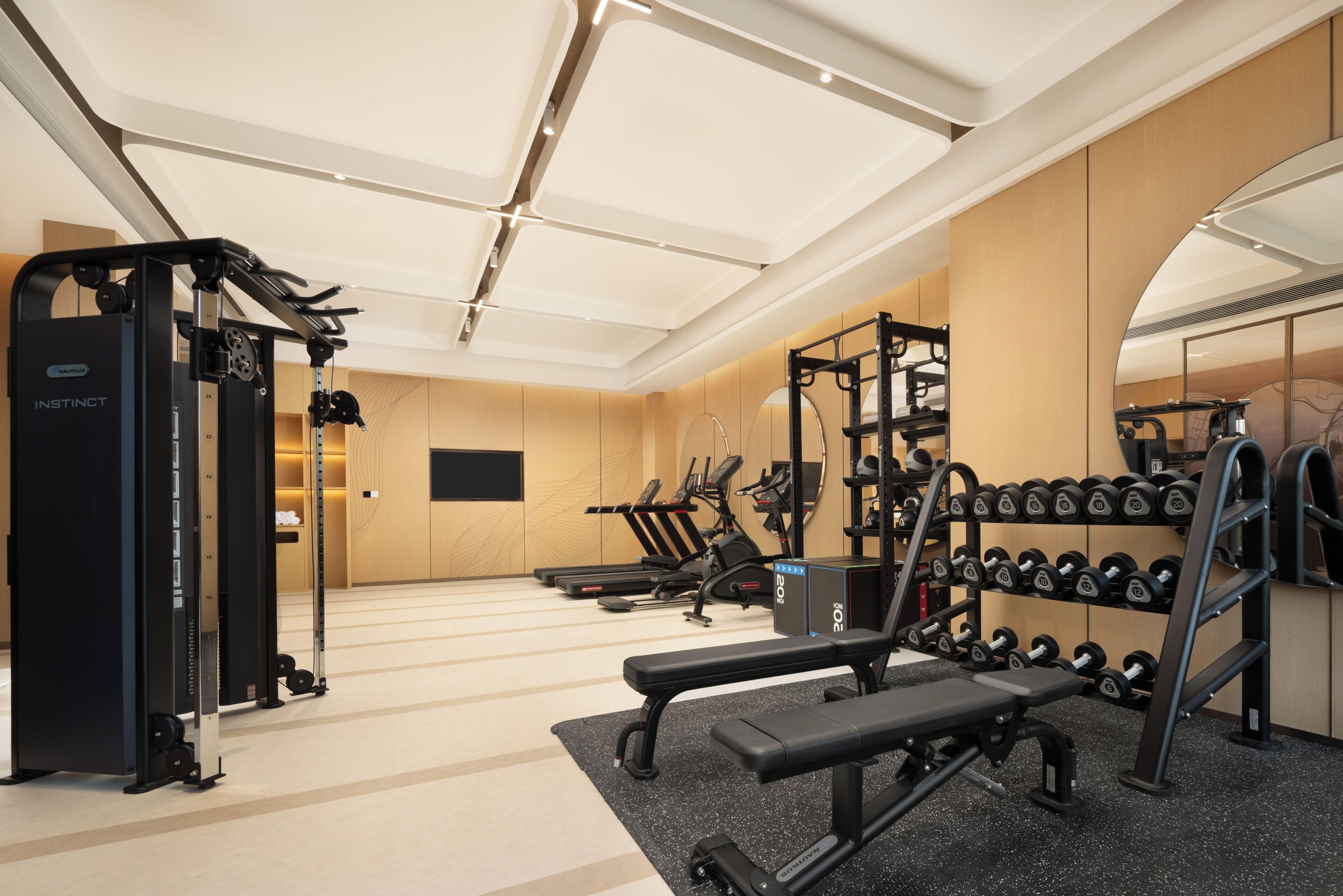 A gym with exercise equipment, a bench, and a wall-mounted rack of dumbbells.