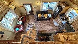 A compact living space with a loft bedroom, a kitchenette, and a seating area with a sofa and armchairs.