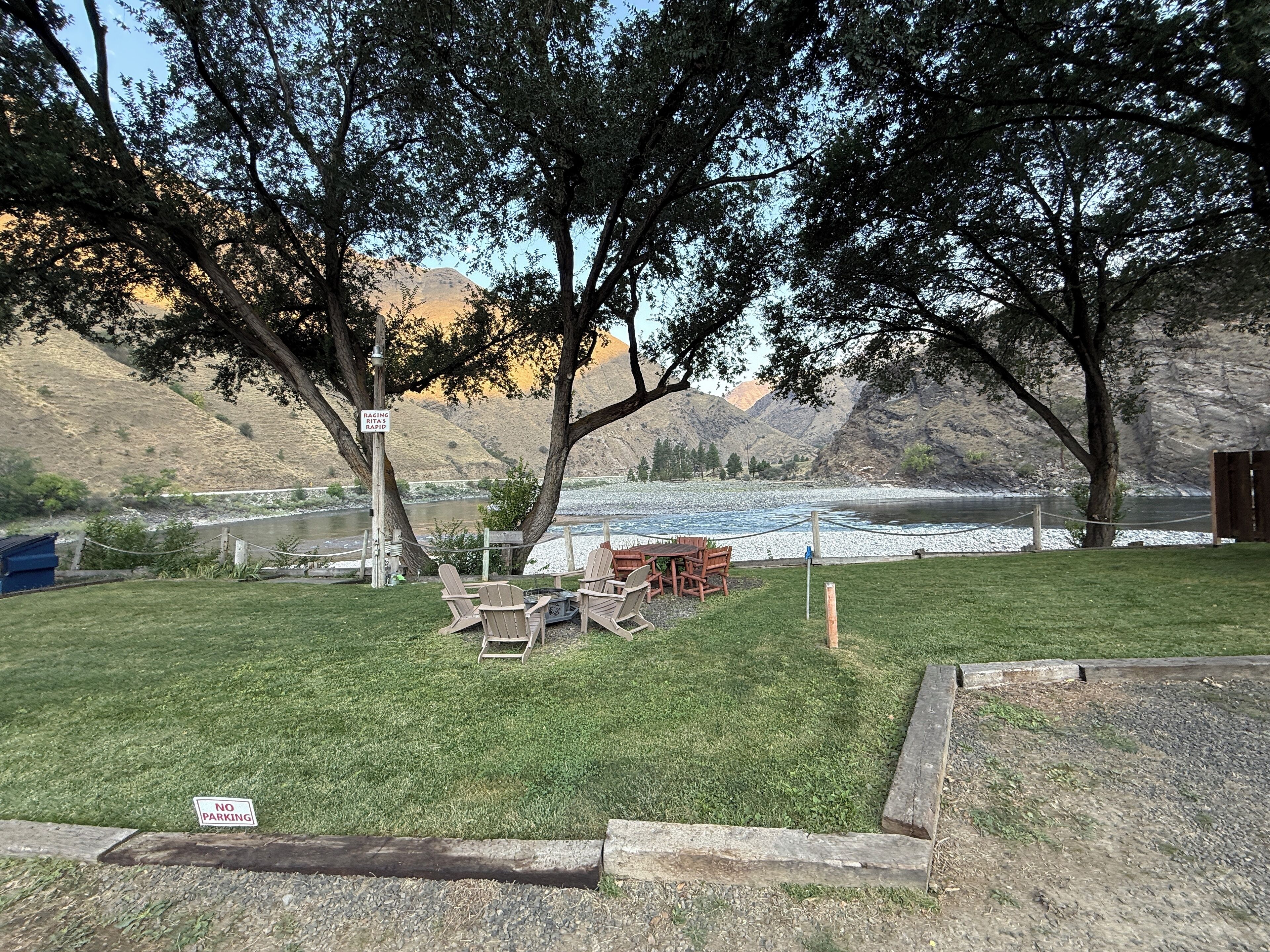 Zona verde con mesas de picnic y un cartel que indica prohibido estacionar.
