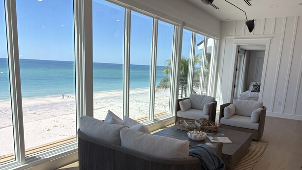 A spacious living room with large windows overlooking a beach, a comfortable sofa, a coffee table, and a chair. - "Dreamy Beachfront Getaway - Your Coastal Sanctuary Awaits!" (Placida)