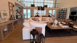 A spacious living area with a large white sofa, a wooden coffee table, and a view of the ocean through large windows. - "Dreamy Beachfront Getaway - Your Coastal Sanctuary Awaits!" (Placida)