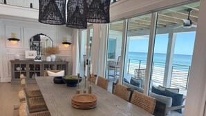 A spacious dining area with a long wooden table, woven chairs, and a view of the ocean. - "Dreamy Beachfront Getaway - Your Coastal Sanctuary Awaits!" (Placida)