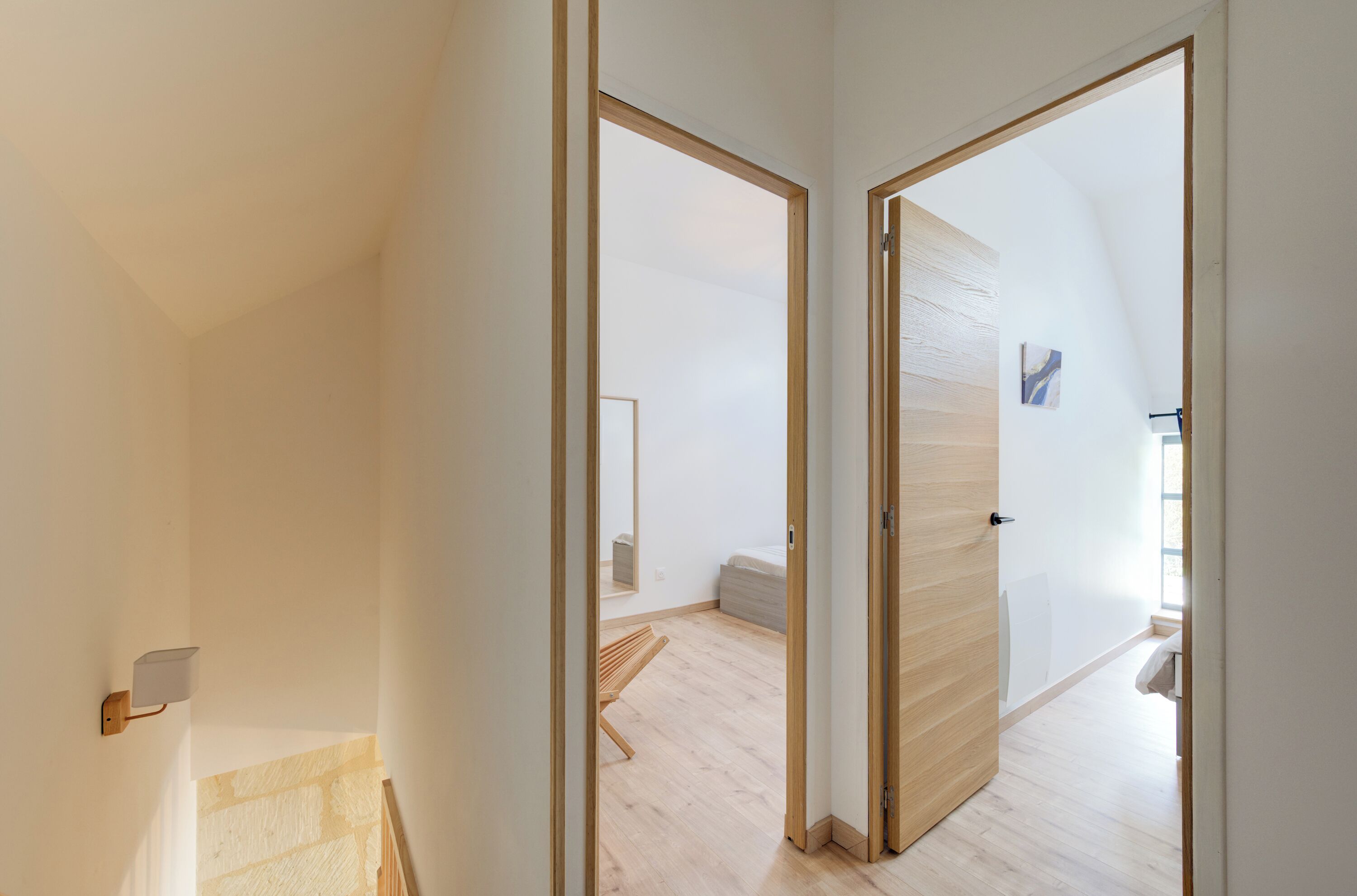 Un intérieur moderne avec un plancher en bois, un banc et un lit en arrière-plan.