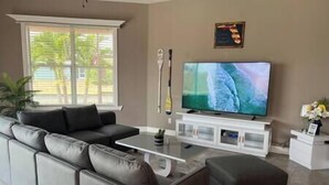 Ein Wohnzimmer mit grauem Sofa, einem Couchtisch, einem Flachbildfernseher und einer weißen Unterhaltungsanlage.