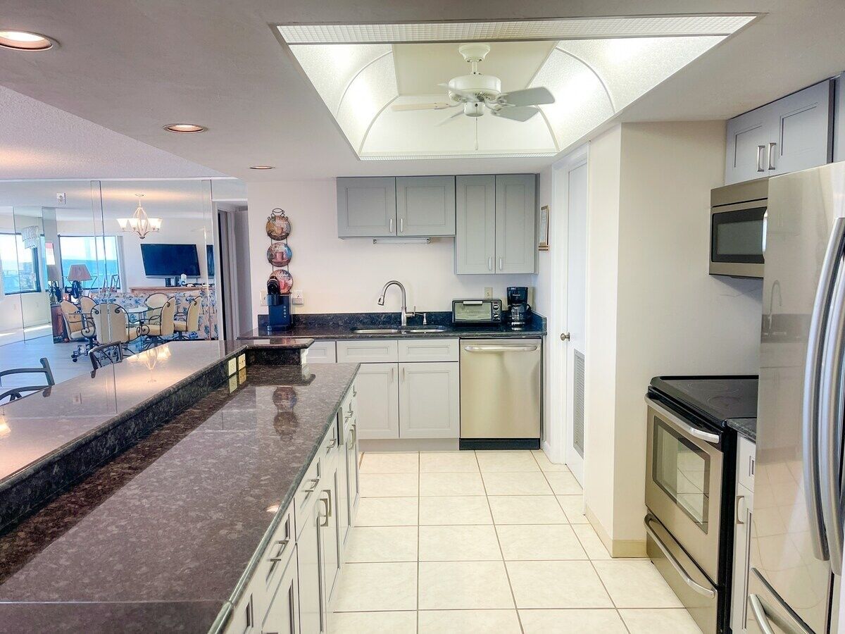 A modern kitchen with a central island, stainless steel appliances, and a ceiling fan.