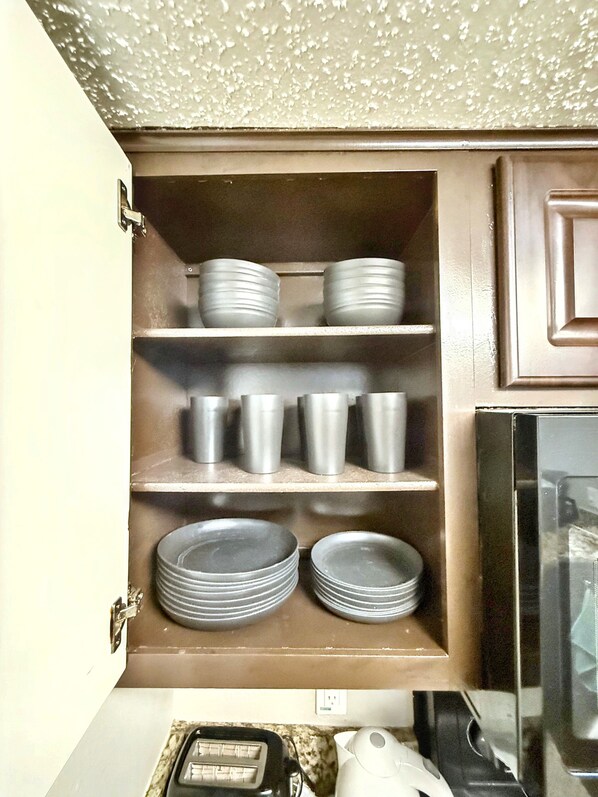 A kitchen with a built-in shelf unit holding plates and cups. - Stylish 1BR w/ Smart TV & Wi-Fi (Addison)