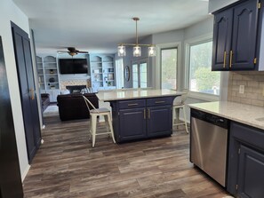 A modern kitchen with dark cabinetry, a central island, and a dishwasher. - Cutie On The Corner (Omaha)
