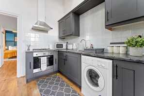 Une cuisine moderne avec des meubles gris, un four encastré, un micro-ondes et un lave-vaisselle.