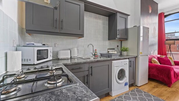 Une cuisine compacte équipée d’une cuisinière à gaz, d’un four à micro-ondes, d’un grille-pain et d’un lave-linge.