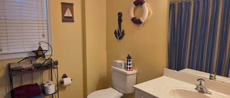 A bathroom with a toilet, sink, and a star-shaped lantern on a metal shelf.