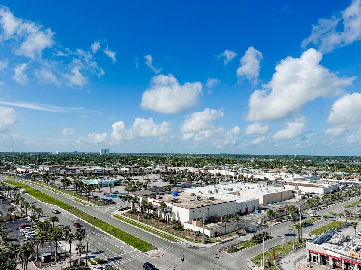 A commercial area with a large building, parking lots, and a clear blue sky.