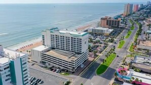 Paisagem costeira urbana com um hotel em destaque, design moderno, praia e área urbana bem cuidada.