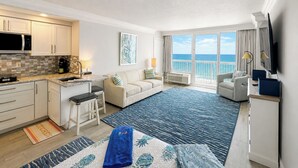 A modern hotel room with a kitchen, a balcony with a view of the sea, a sofa, and a TV. - The Reserve | Oceanfront Studio | Private Balcony (Daytona Beach)