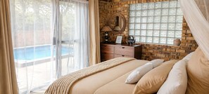 Une chambre à coucher comprenant un lit, une commode, un miroir et une fenêtre ornée de vitraux décoratifs.