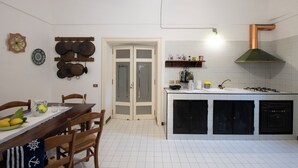 Uma cozinha compacta com uma ilha central, uma área de refeições com cadeiras, e uma porta que dá para outro espaço.
