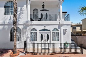 Un immeuble de deux étages doté d’un balcon, de grandes fenêtres et d’une entrée fermée par un portail.
