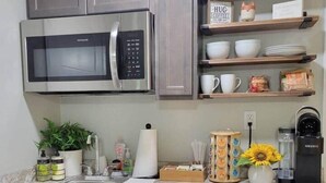 A modern kitchen with stainless steel appliances, wooden shelves, and a coffee maker. - Northgate Studio - 1 block from TAMU! (College Station)